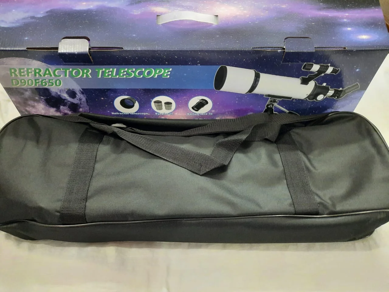 Carry bag in front of the retail box, which shows the telescope, eyepieces and 3x Barlow lens icons.