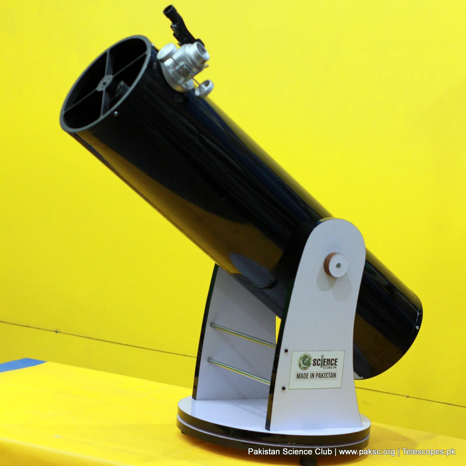 Telescope tilted high on its base, Made in Pakistan sticker on the rocker box