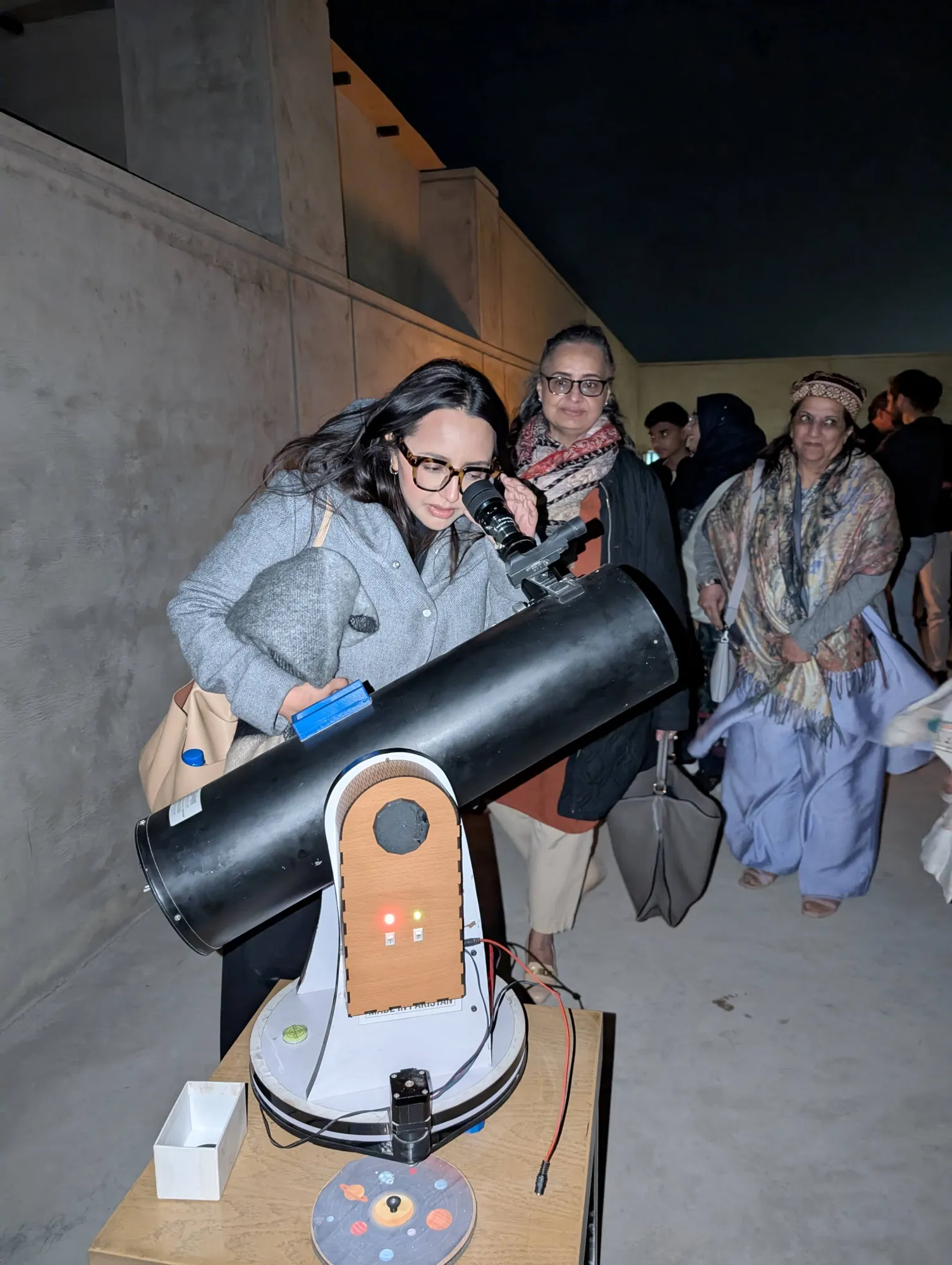 A visitor looks through the RVision GT 6-750 at a rooftop astronomy night.